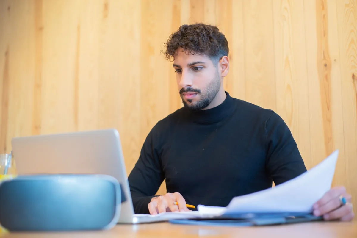 Office manager comparing printed invoices against a laptop