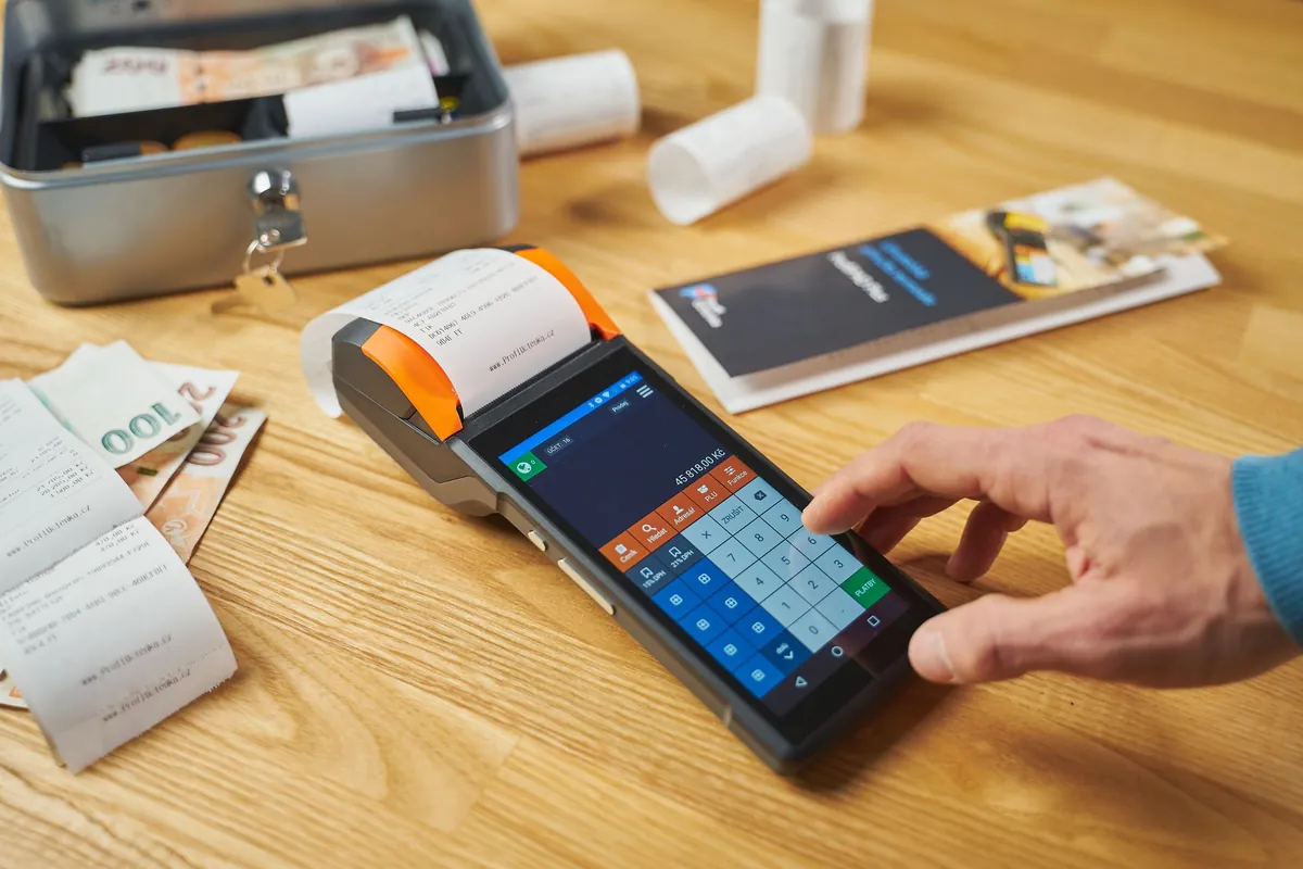 Card payment terminal and printed receipts on a wooden desk
